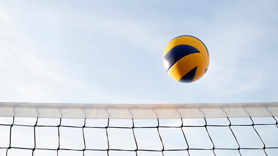A volleyball flies over a net