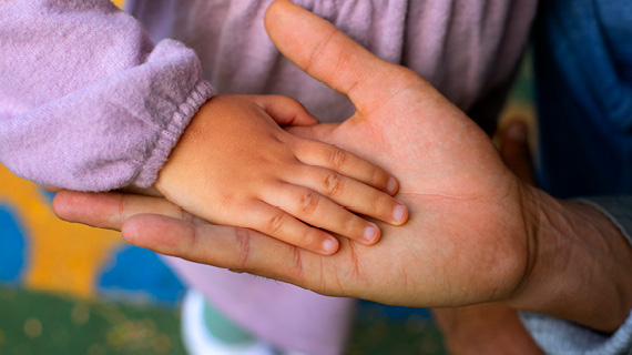Eine Kinderhand liegt auf einer Hand eines Erwachsenen